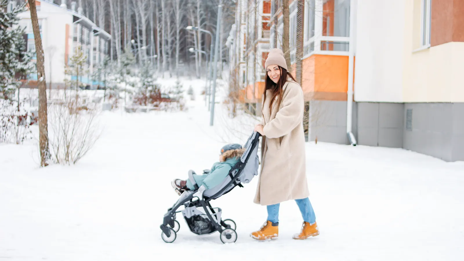 Förälder med barnvagn på snöig vinterväg